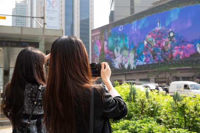 아트코리아랩 수퍼 테스트베드 전시에서 시민들이 도재인, 이뿌리, 하지수 작가의 3D 아나모픽 미디어아트 작품 ‘남산숨길(Namsan Breeze)’을 사진으로 담고 있다.