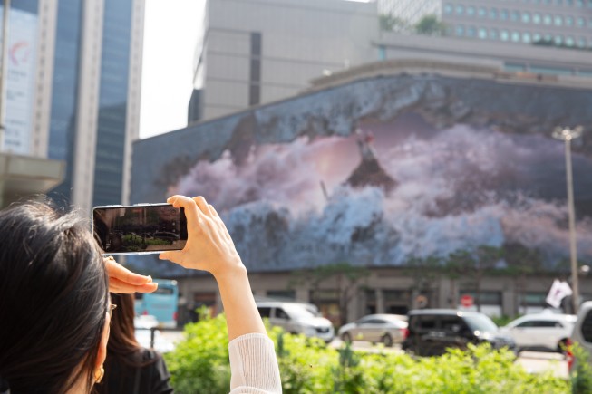 시민과 관람객이 명진영, 이윤서 작가의 3D 아나모픽 미디어아트 작품 ‘불멸의 파도(Immortal Wave)’를 사진으로 담고 있다.